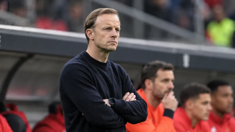 Een lid van de technische staf van Standard applaudisseert langs de zijlijn.