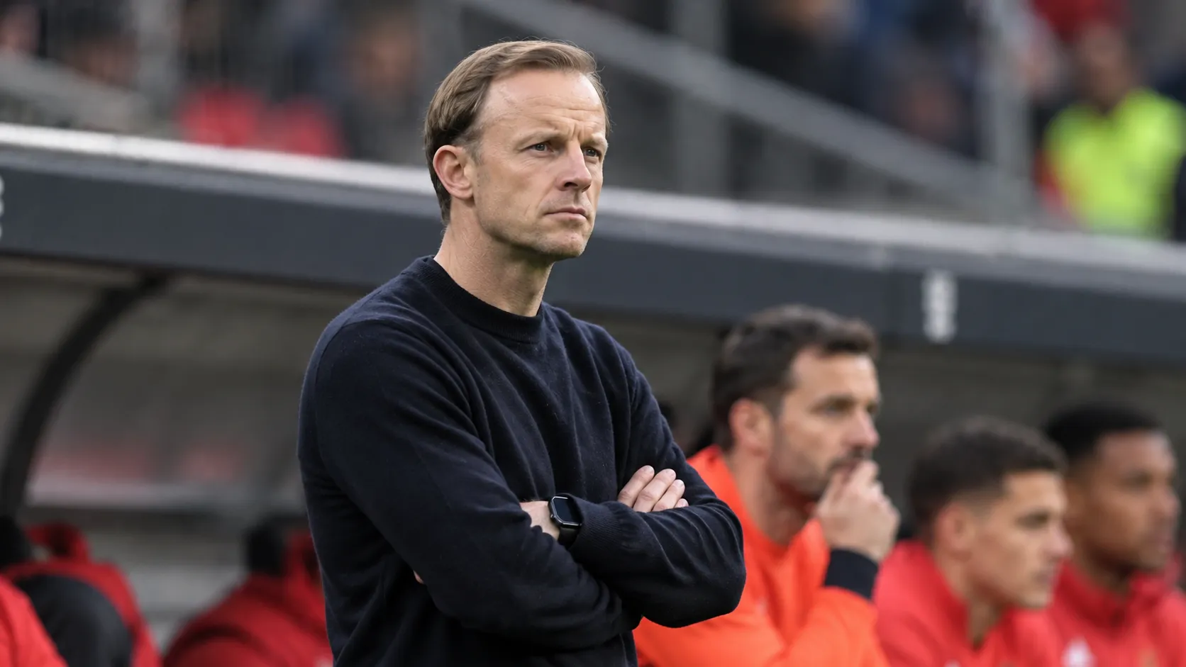Een lid van de technische staf van Standard applaudisseert langs de zijlijn.