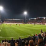 KV Kortrijk in rood-witte sfeer in het Guldensporenstadion, met het veld en de iconische staantribune Vak I.