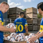 Drie voetballers tonen blauwe en gele Europese shirts naast wedstrijdballen.