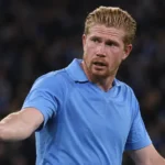 Kevin De Bruyne in een blauw Napoli-shirt kijkt tijdens een wedstrijd richting de zijlijn.
