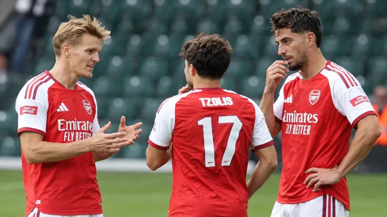 Drie voetballers in rood-witte tenues tijdens een gezamenlijke opwarming in een stadion.