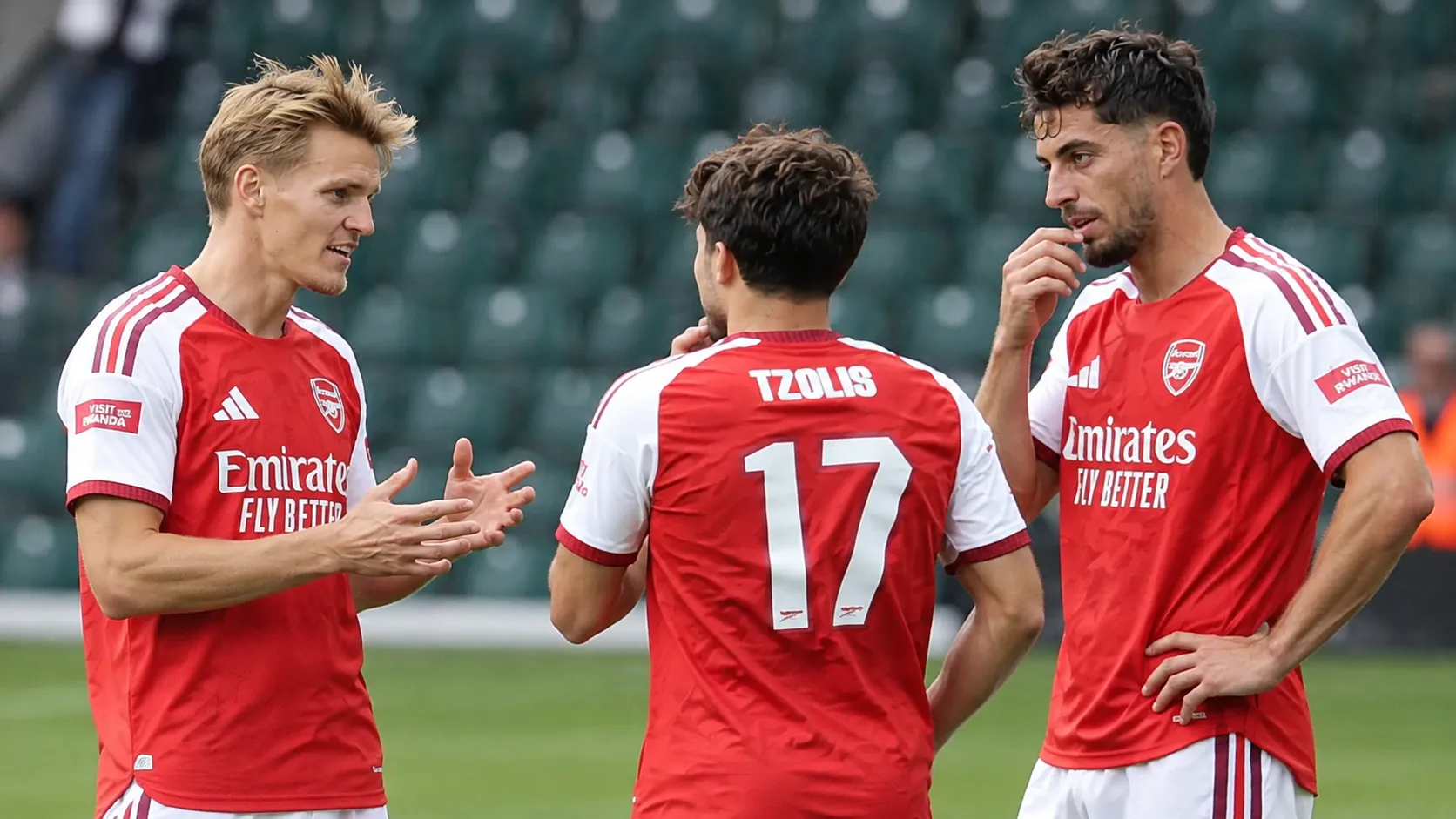 Drie voetballers in rood-witte tenues tijdens een gezamenlijke opwarming in een stadion.