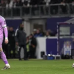 Twee voetballers wandelen na een wedstrijd op het veld.