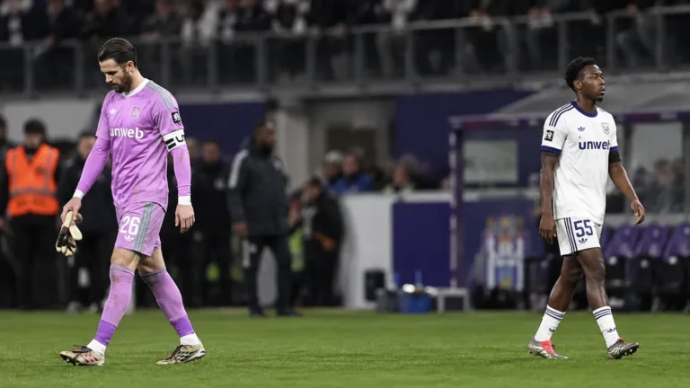 Twee voetballers wandelen na een wedstrijd op het veld.