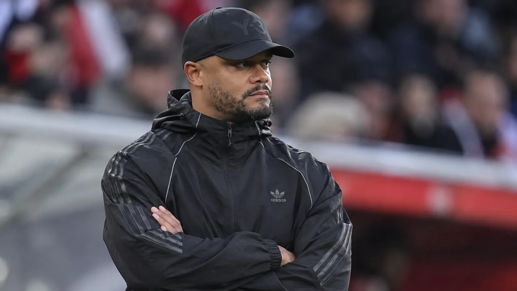 Vincent Kompany staat geconcentreerd langs de zijlijn in een stadion.