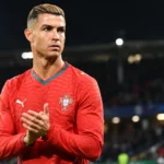 Cristiano Ronaldo in het Portugese shirt langs de rand van een verlicht stadion.