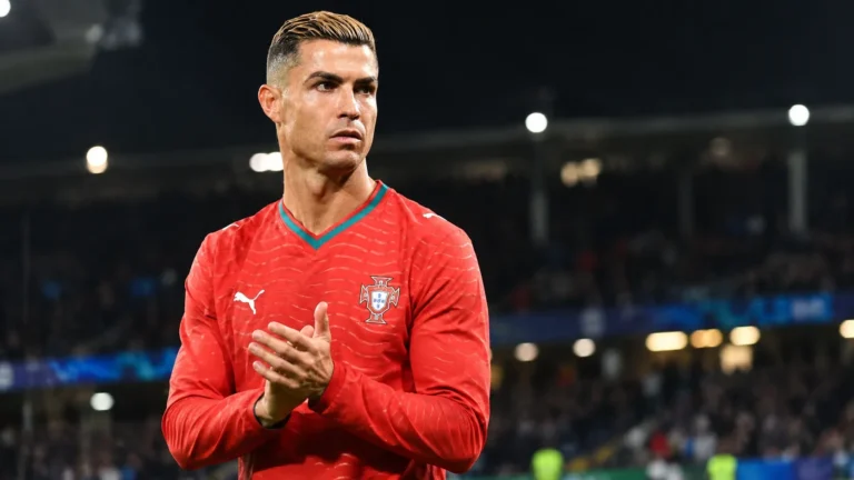 Cristiano Ronaldo in het Portugese shirt langs de rand van een verlicht stadion.