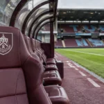 Lege dug-out van Burnley op Turf Moor met een clubembleem op een vaste zitplaats.
