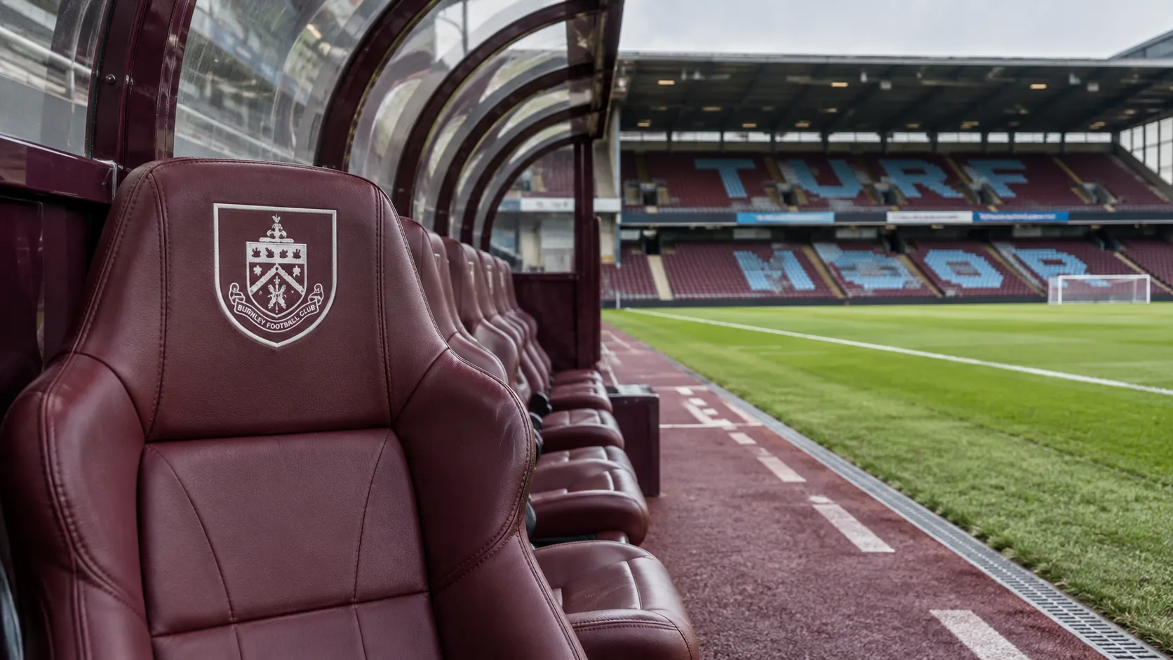 Lege dug-out van Burnley op Turf Moor met een clubembleem op een vaste zitplaats.