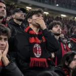 Teleurgestelde AC Milan-supporters op de tribune van San Siro met een Milan-sjaal.