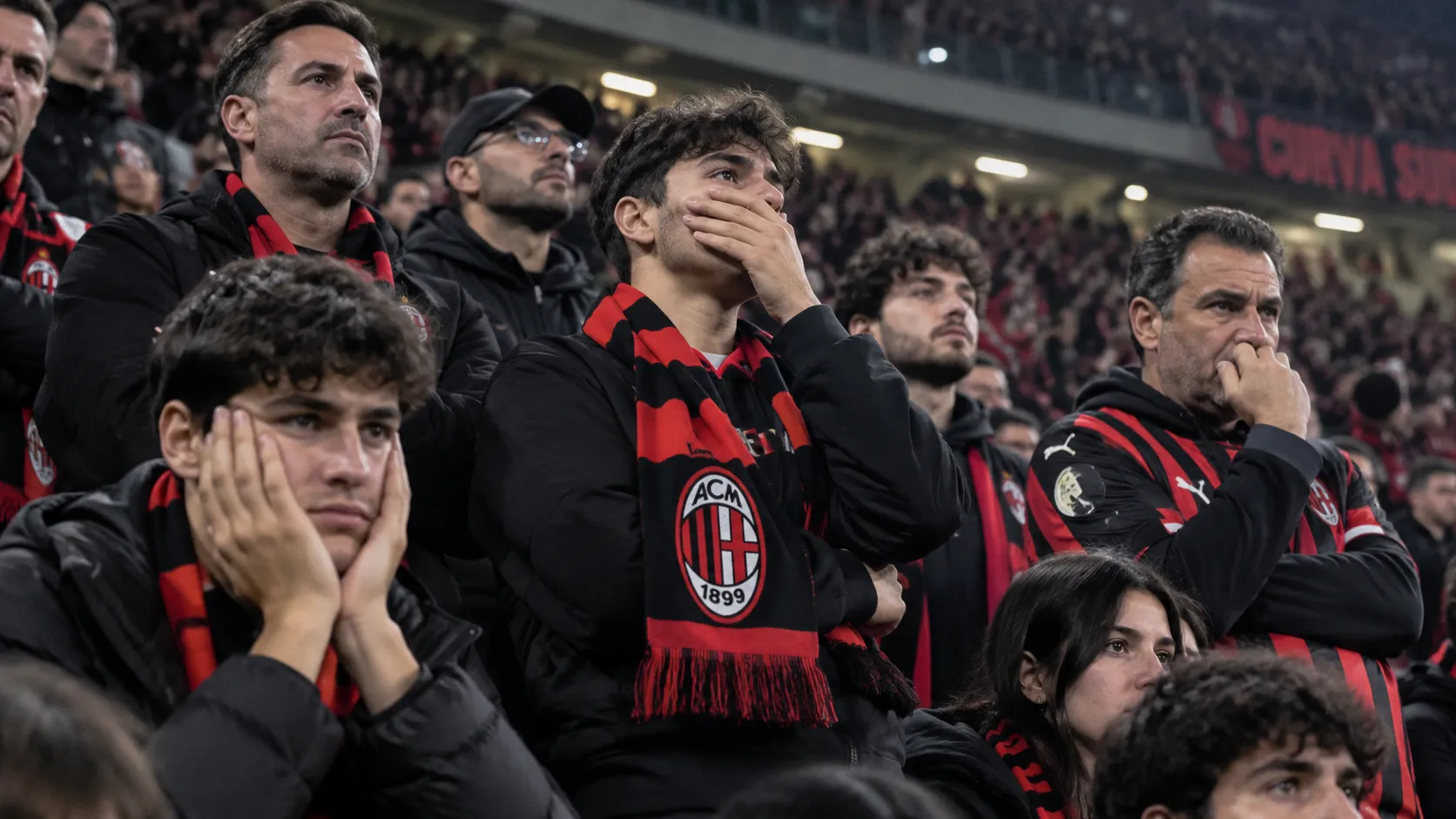 Teleurgestelde AC Milan-supporters op de tribune van San Siro met een Milan-sjaal.