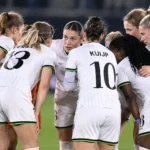 Een groep speelsters van OHL Women overlegt op het veld tijdens een Champions League-wedstrijd.