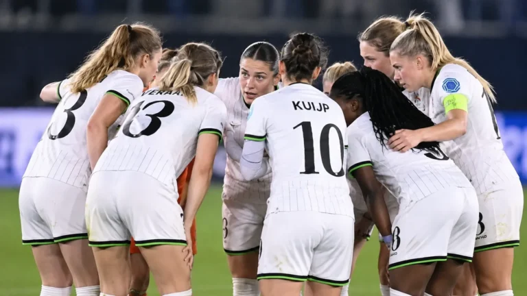 Een groep speelsters van OHL Women overlegt op het veld tijdens een Champions League-wedstrijd.