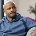Vincent Kompany zit rustig binnenshuis in een blauwgrijze sporthoodie.