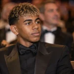 Lamine Yamal zit in formele kledij in de zaal van een voetbalgala.