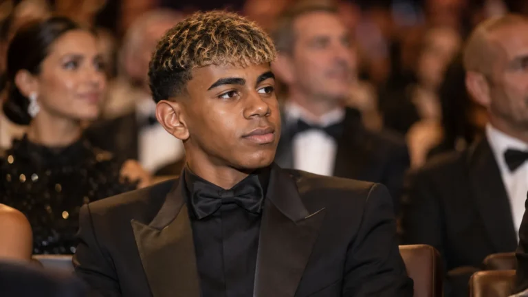 Lamine Yamal zit in formele kledij in de zaal van een voetbalgala.