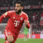 Een Bayern München-speler in rood tenue tijdens een bekerwedstrijd in een vol stadion.