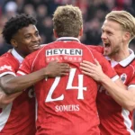 Een groep Antwerp-spelers in rode wedstrijdshirts viert samen op het veld.