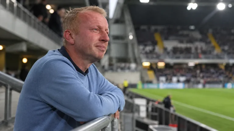 Sven Vandenbroeck staat in een stadion en kijkt bedachtzaam naast de camera.