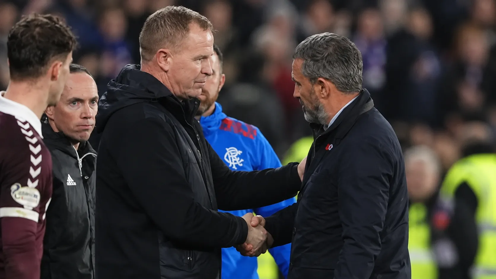 Twee coaches geven elkaar na afloop de hand op de zijlijn.