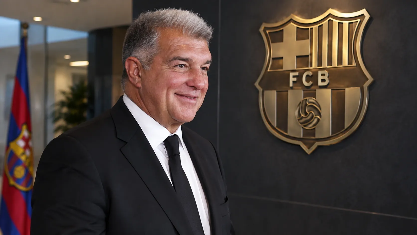 Een clubfunctionaris in donker kostuum in een institutionele ruimte van FC Barcelona.
