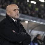Een Juventus-trainer in donkere jas aan de rand van het veld.