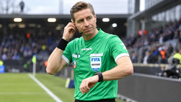 Een scheidsrechter in groen tenue voert voor de aftrap een controle uit op het veld.