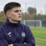 Amando Lapage in een donker trainingsjasje van Anderlecht naast het trainingsveld.