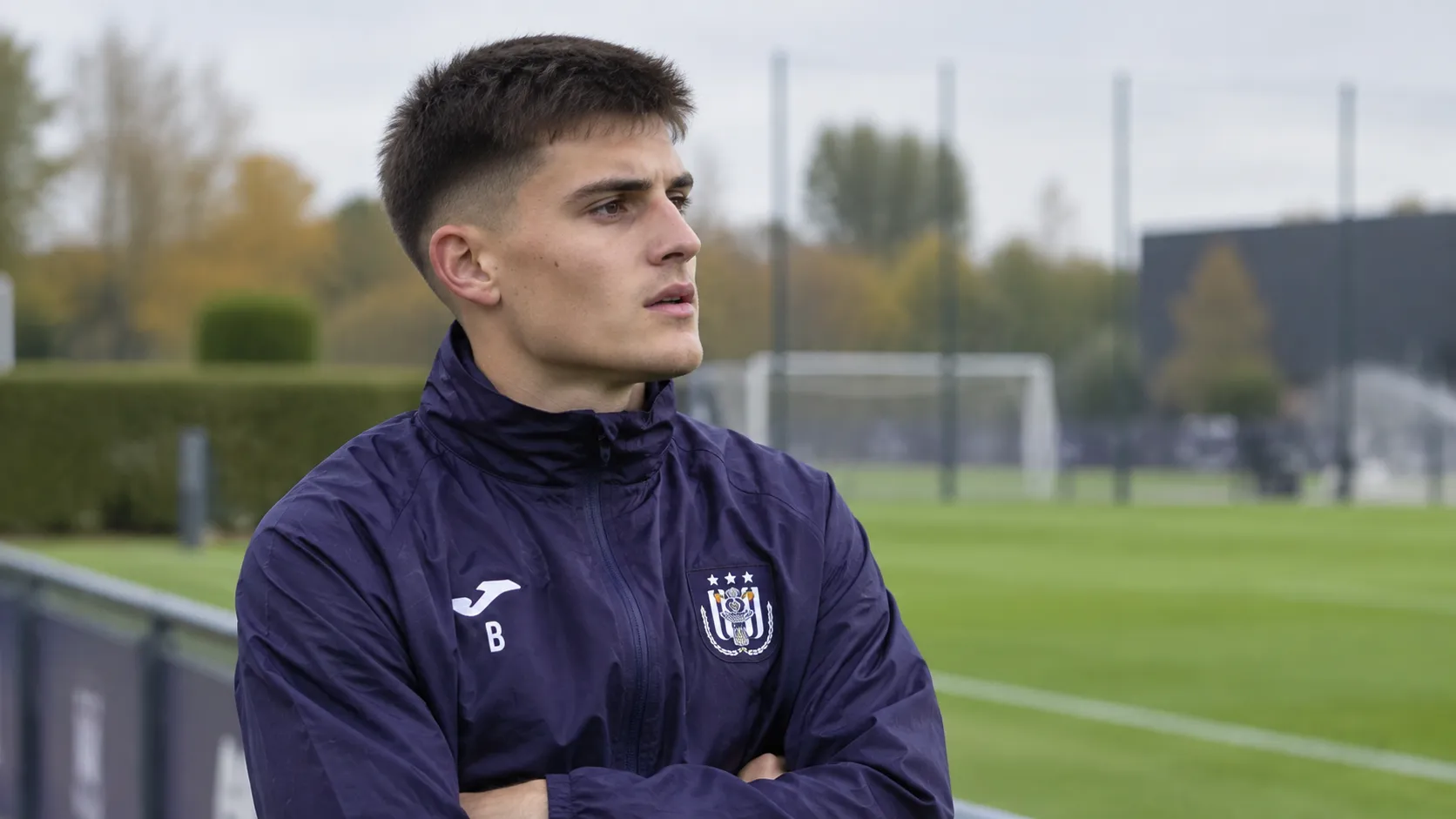 Amando Lapage in een donker trainingsjasje van Anderlecht naast het trainingsveld.