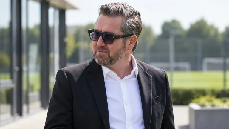 Een niet nader genoemde voetbalofficial in pak buiten een voetbalcomplex.