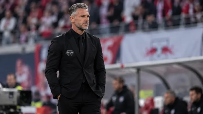 Een coach van RB Leipzig in zwarte kleding aan de zijlijn tijdens een wedstrijd.