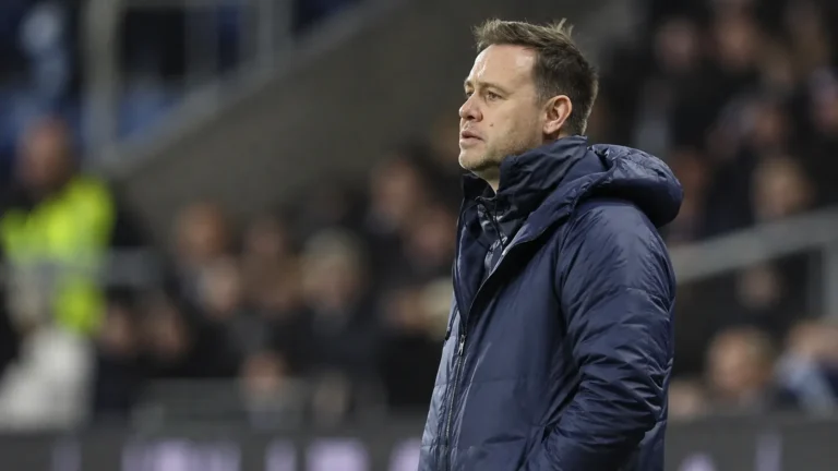 Michael Beale in een blauwe jas aan de zijlijn van een voetbalstadion.