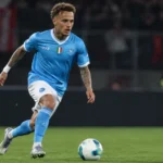 Noa Lang dribbelt in het lichtblauwe shirt van Napoli tijdens een avondwedstrijd.