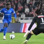 Een speler van KRC Genk in blauw in actie voor doel, met een doelman op de voorgrond.