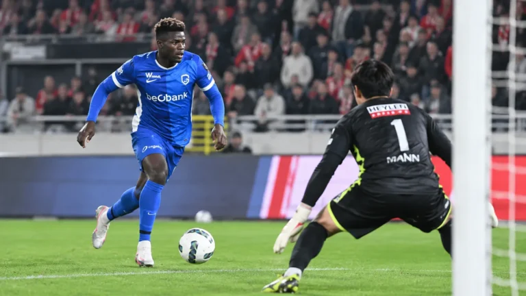Een speler van KRC Genk in blauw in actie voor doel, met een doelman op de voorgrond.