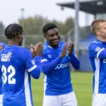 Een groep KRC Genk-spelers applaudisseert samen op het veld.