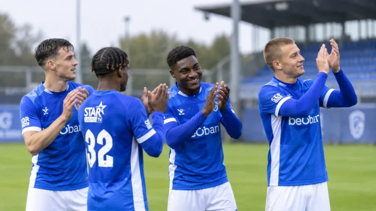 Een groep KRC Genk-spelers applaudisseert samen op het veld.