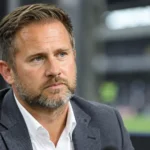Jesper Fredberg in professionele kledij bij een voetbalstadion.