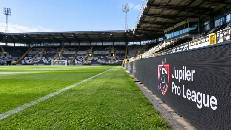 Een leeg stadionvak met een Jupiler Pro League-wedstrijdbord langs het veld.