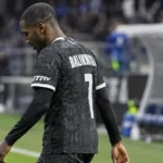 Michel-Ange Balikwisha van KAA Gent wandelt langs de zijlijn in wedstrijdtenue.