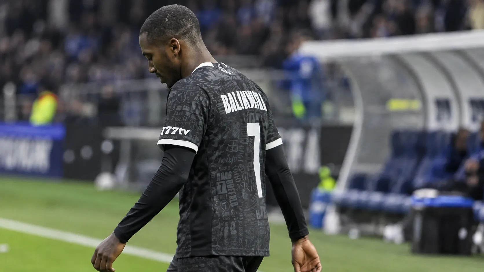 Michel-Ange Balikwisha van KAA Gent wandelt langs de zijlijn in wedstrijdtenue.
