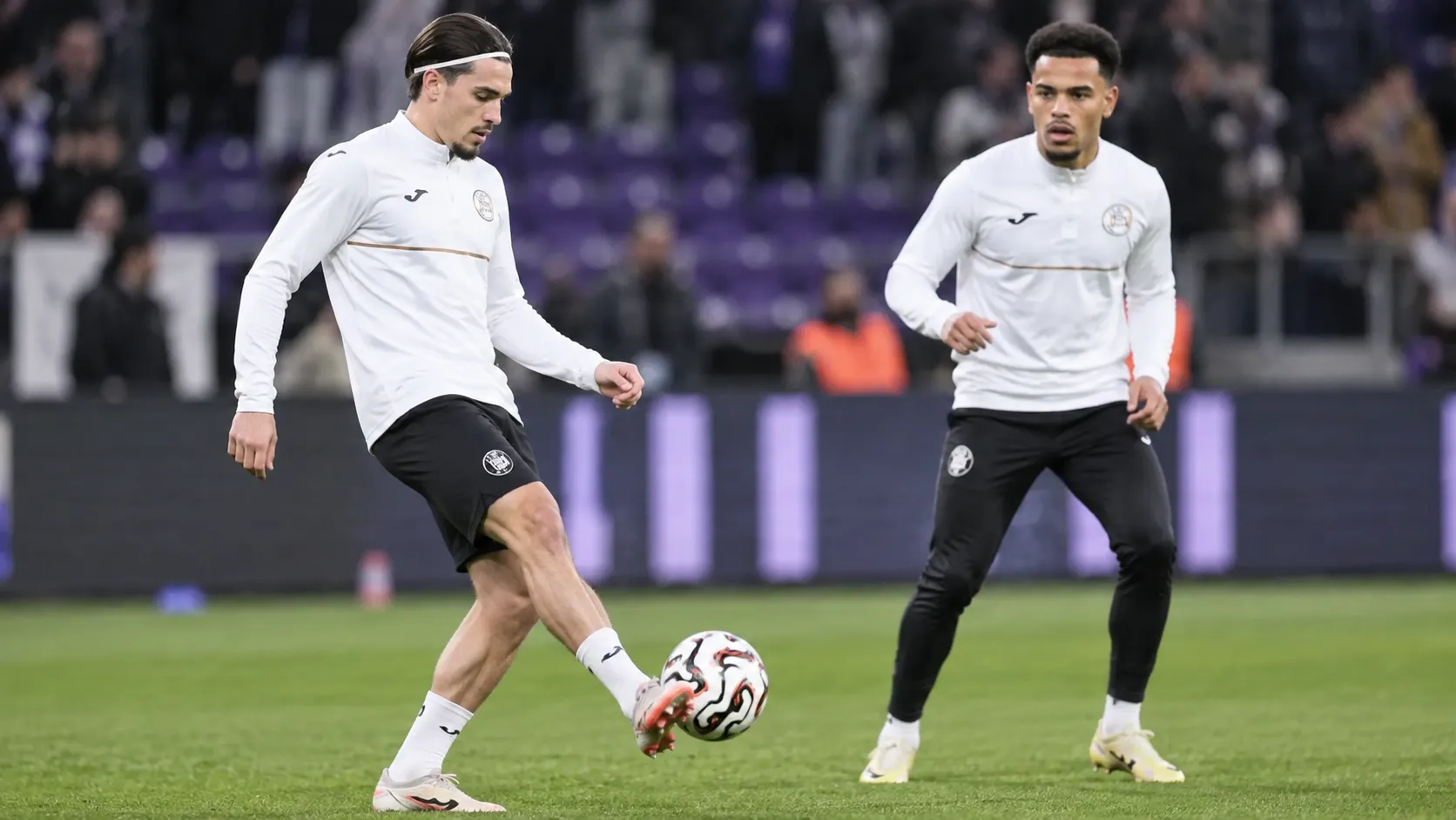 Twee Anderlecht-spelers warmen op met een bal op het veld.
