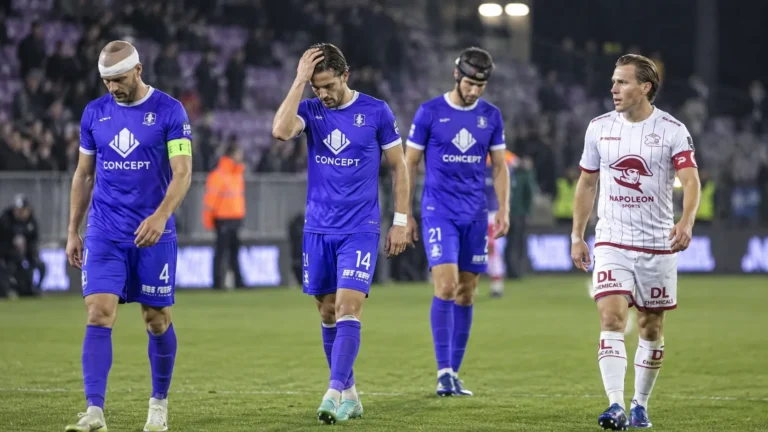 Spelers in paarse en witte tenues verlaten na een wedstrijd het veld.