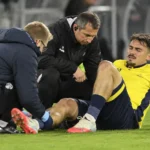 Een Union-speler krijgt langs het veld verzorging van twee stafleden.