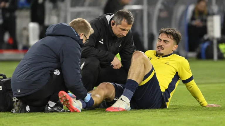 Een Union-speler krijgt langs het veld verzorging van twee stafleden.
