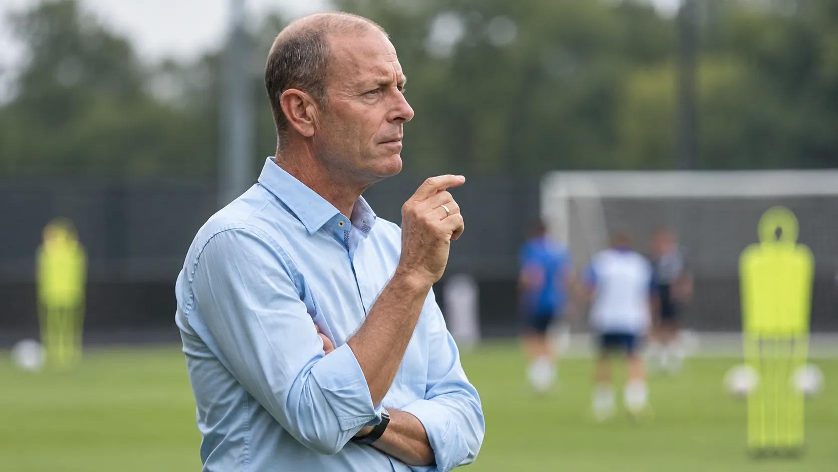 Jess Thorup kijkt geconcentreerd toe vanaf de zijlijn van een voetbalveld.