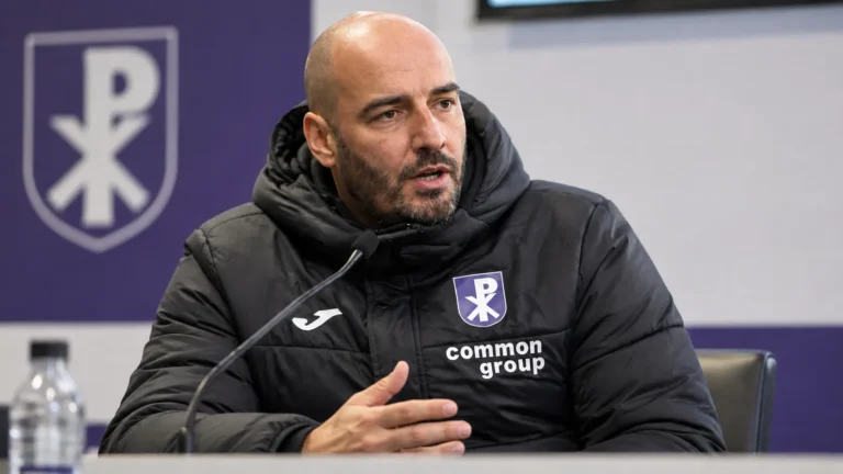 Stijn Stijnen spreekt tijdens een persconferentie in een donkere clubjas.