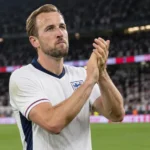 Harry Kane applaudisseert in het witte tenue van Engeland op het veld.