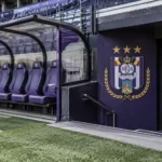 Lege dug-out van RSC Anderlecht met een clubembleem op de wand naast de tunnel.
